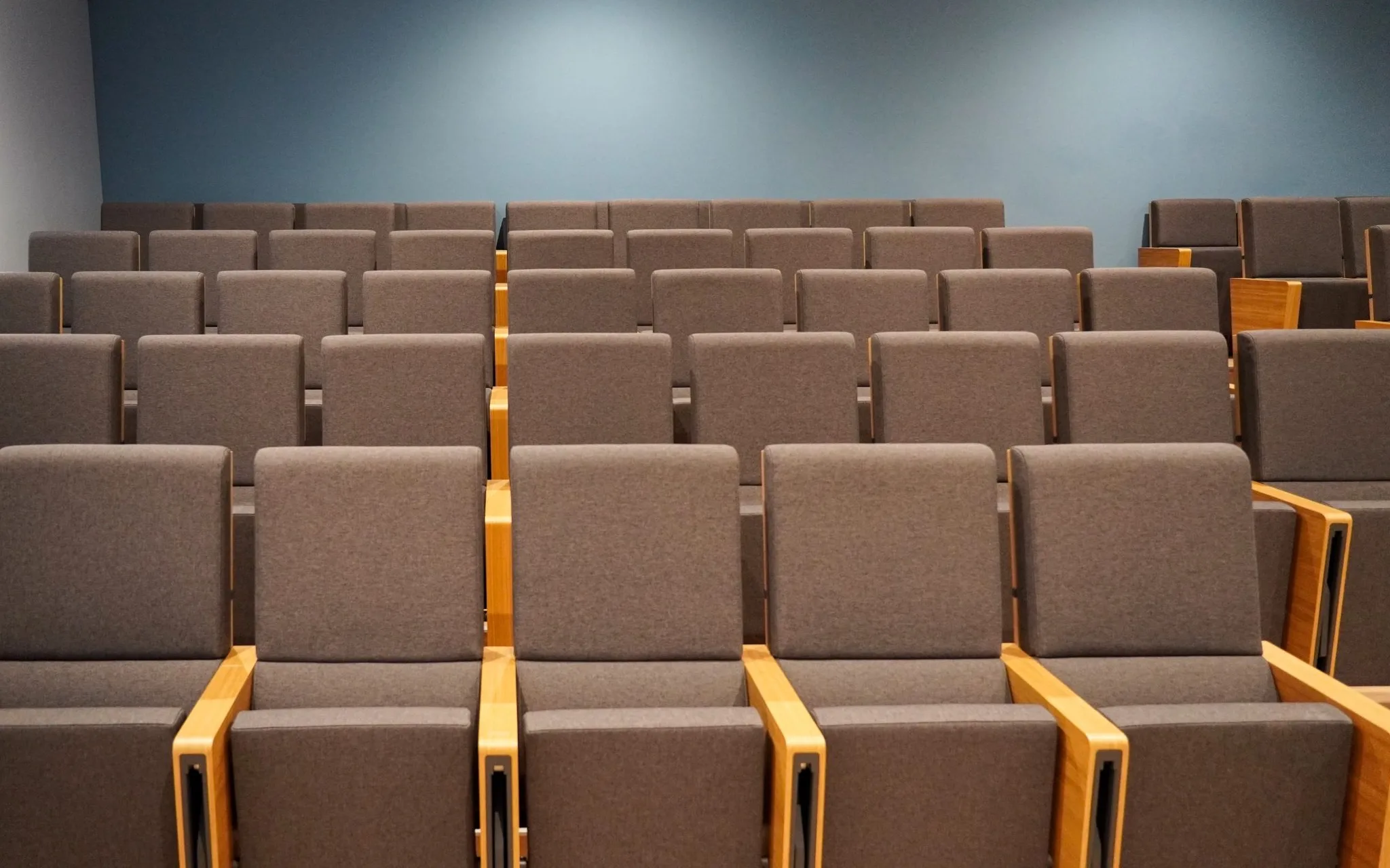 Rows of empty gray upholstered seats in a small lecture hall